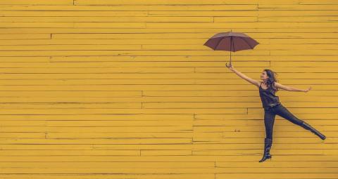 woman with umbrella on a yellow wall